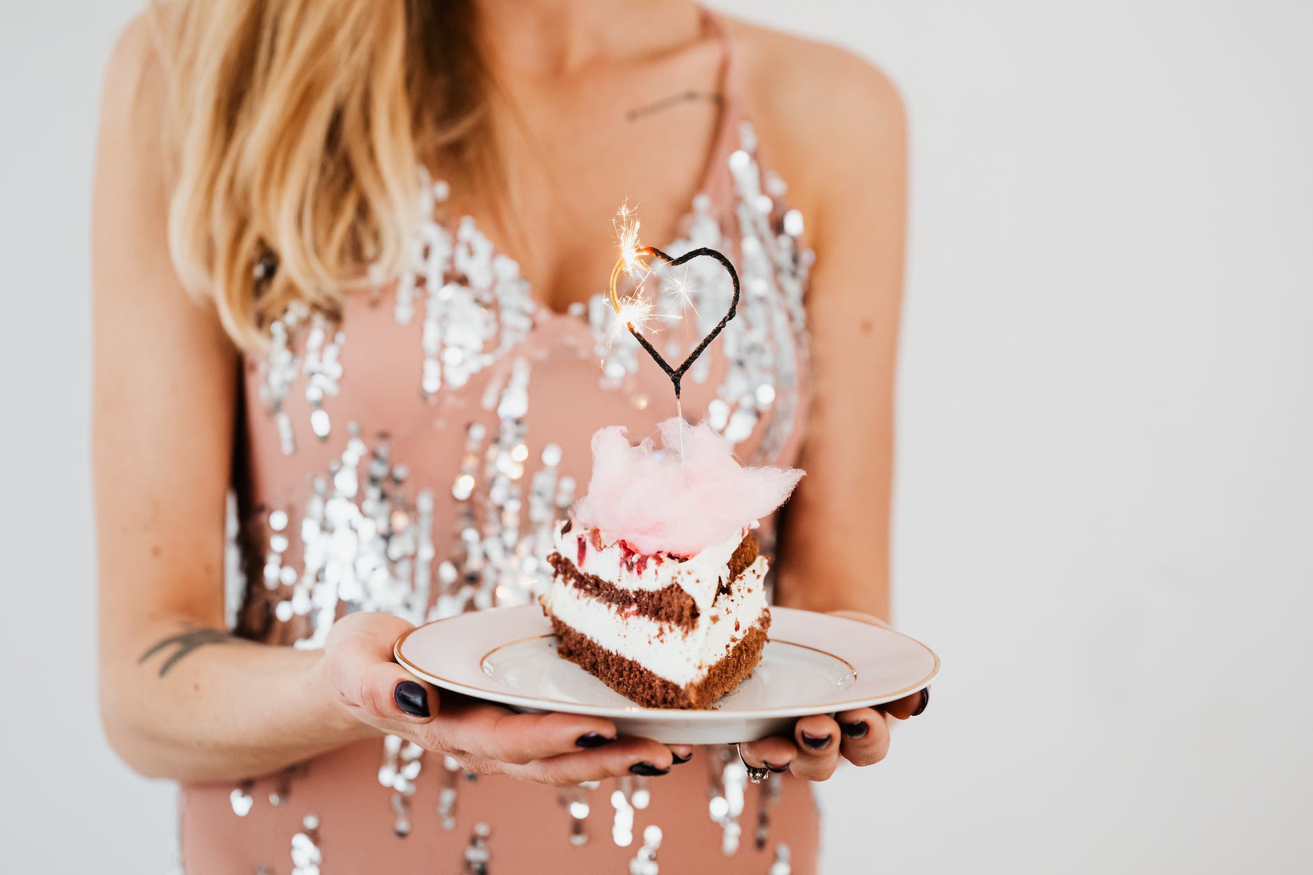 woman holding a slice of cake with heart shaped sparkler