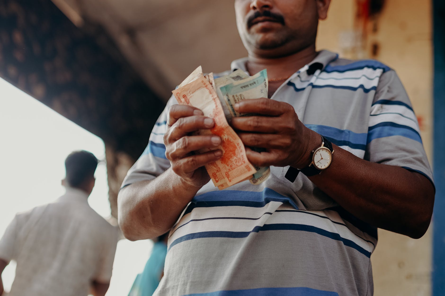 man in blue and white stripe polo shirt holding banknote