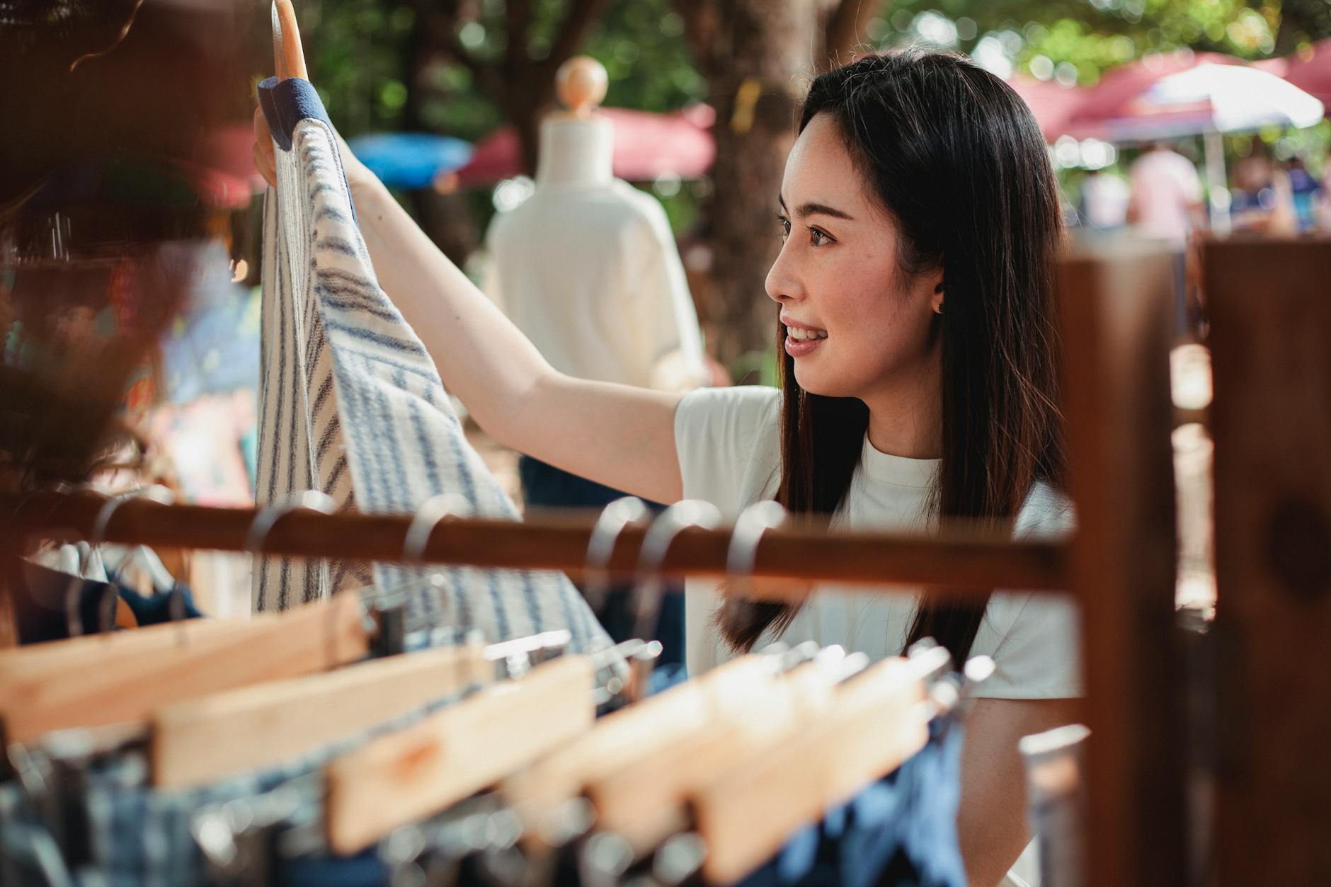 young asian woman choosing clothes in street market